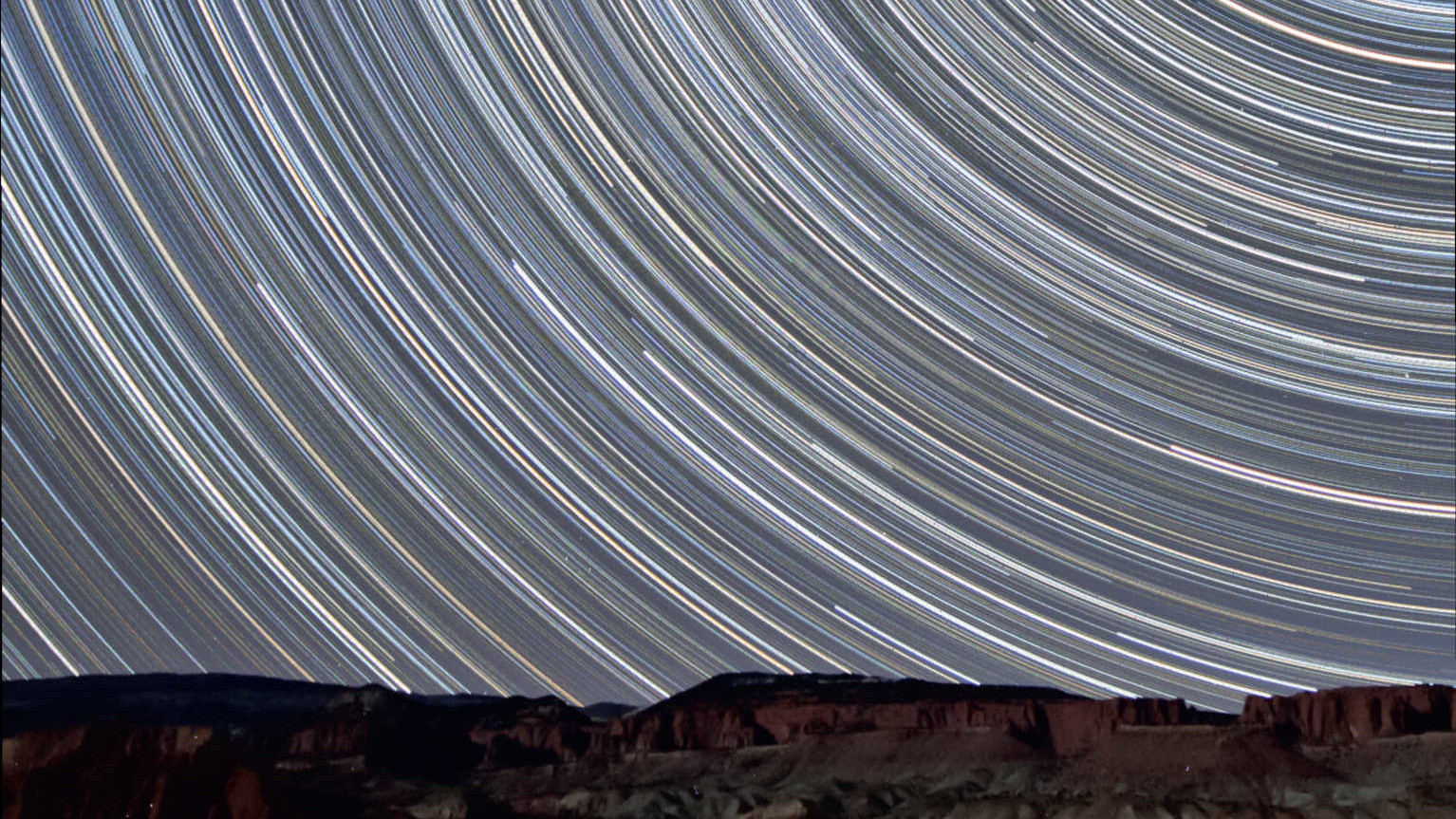 Wenige Meilen vor dem Capitol Reef Nationalpark in Utah (USA) entstanden diese Strichspuraufnahmen mit Blick nach Norden, die die Wanderung
der Sterne über den vom zunehmenden Mond beleuchteten roten Sandsteinfelsen zeigt. In diesem Summenbild sind 350 Aufnahmen mit einer Belichtungszeit
von je 90 Sekunden kombiniert (Gesamtbelichtungszeit: 525 Minuten = 8,75 Stunden). Entstanden ist das Bild mit einem 10-20mm Objektiv (bei 10mm
und f/4) an einer Canon DSLR vom Typ 450D. U. Dittler