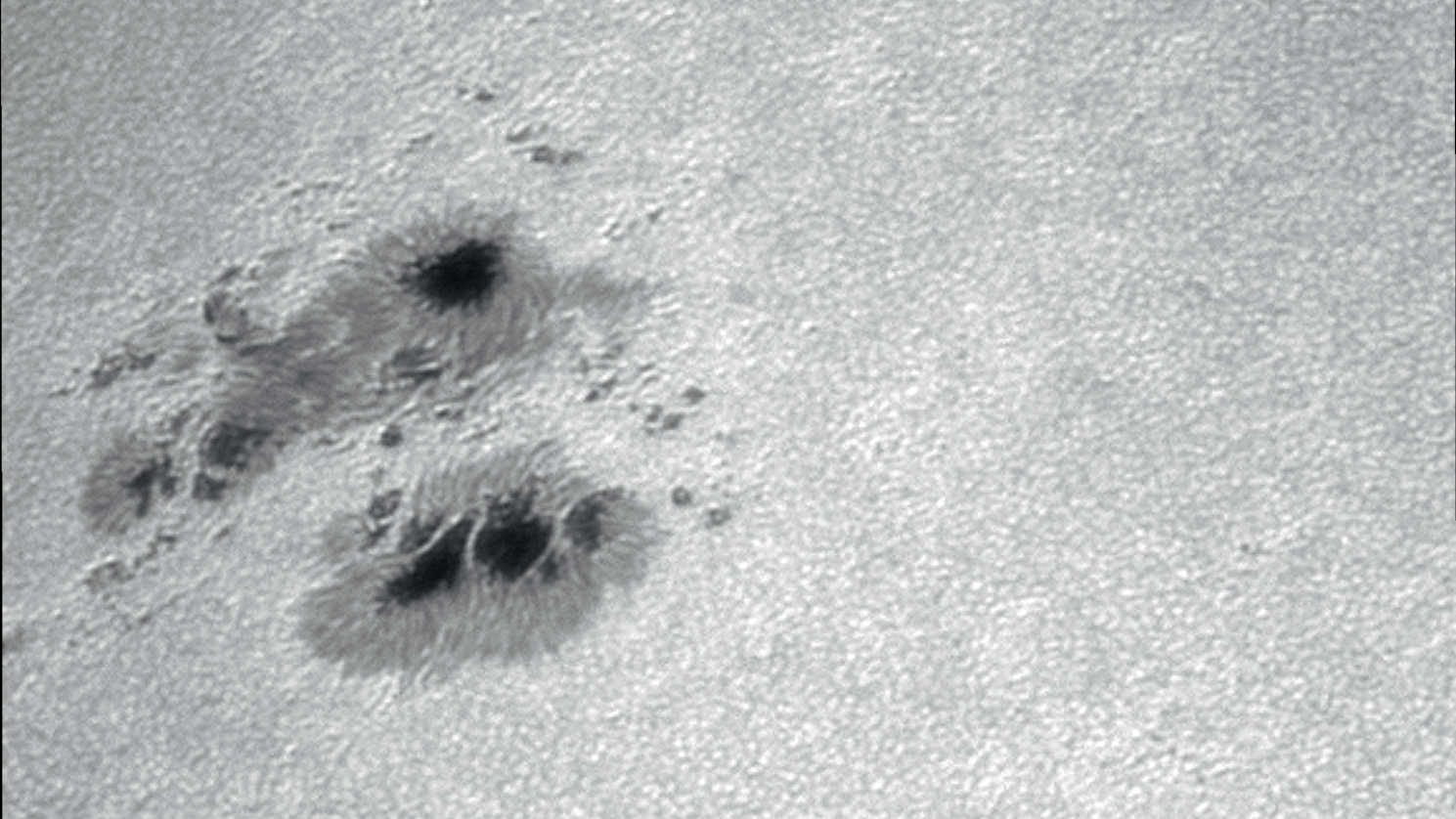 Taches solaires dans la lumière blanche. La photo montre nettement les différentes structures de chacune des taches. Photo réalisée avec une caméra CCD non refroidie placée sur un télescope d’une ouverture de 130 mm, distance focale 3 250 mm. Pour cet empilement d’images, 500 images prélevées d’une séquence de 2 500 prises de vues ont été utilisées. U. Dittler